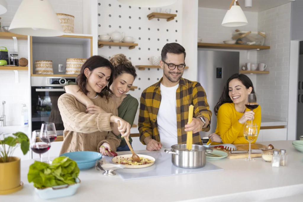 Friends cooking and enjoying a meal together in a bright kitchen—Truxtun open-concept kitchen design