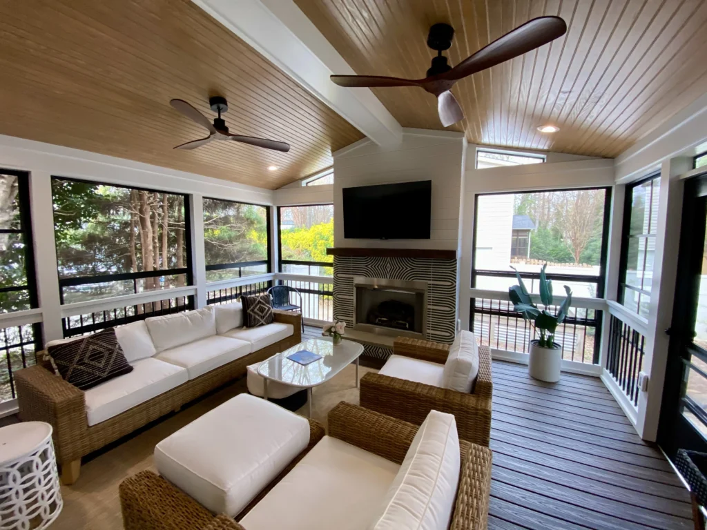 Cozy sunroom with fireplace, wicker seating, and ceiling fan—Truxtun enclosed porch design