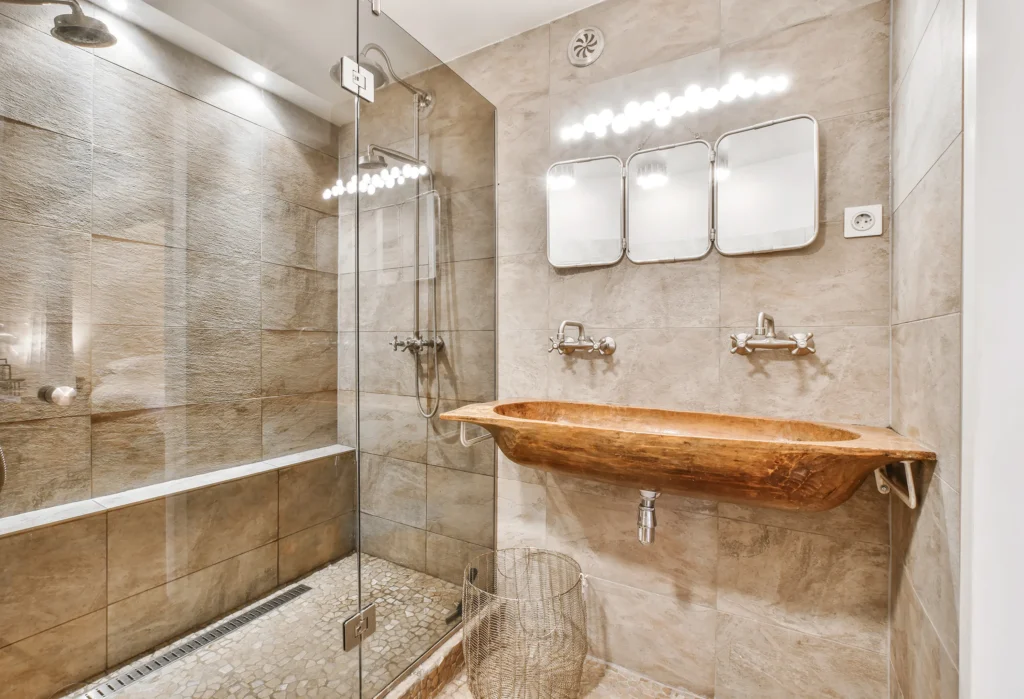 Rustic-style custom bathroom with walk-in glass shower and handcrafted wooden sink basin, designed by Truxtun Building Group